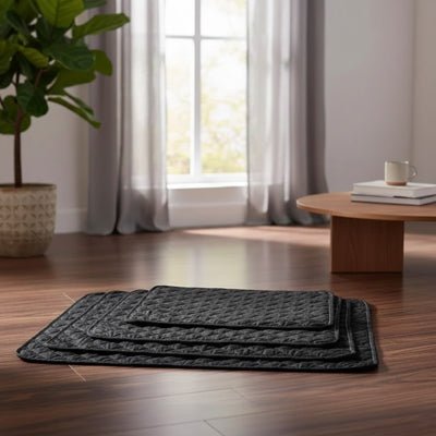 Alèse lavable chiot hygiène, imperméable, 4 couches absorbantes, surface douce qui reste toujours sèche résistante aux griffes et lavable en machine pour chiot de petite à grande taille,durable et polyvalent comme protection de la literie, couchage, sol, siège voiture, etc- gros plan sur l'alèse douce et confortable de couleur noire en 3 tailles S, M et L empilés sur le sol du salon de l'appartement