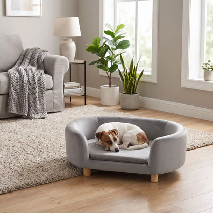 Canapé gris pour chiot et chien, structure en bois de bouleau , dossier haut et entourant à 360° au design moderne et arrondi avec son coussin en éponge 100% coton haute densité et ergonomique déhoussable et lavable en machine, housse en velours douce et résistante, sur pied en bois massif pour chien de petite taille- un chien de petite race active qui dort paisiblement sur le canapé ergonomique au design moderne de couleur gris dans le salon moderne et design de la maison