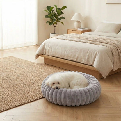 Coussin-anti-stress-chien-chiot-cocon-antiderapant, rembourrage 100% coton haute densité, housse en velours doux et hypoallergénique,lavable en machine, lit rond en forme de donut avec rembord surélevé entourant à 360° en peluche douce et disponible en 4 tailles du XS au XL pour chien de petite à grande taille-un petit chien qui dort niché dans son coussin rond de taille M, apaisant et chaud ergonomique au rembourrage 100% coton haute densité dans la chambre de la maison