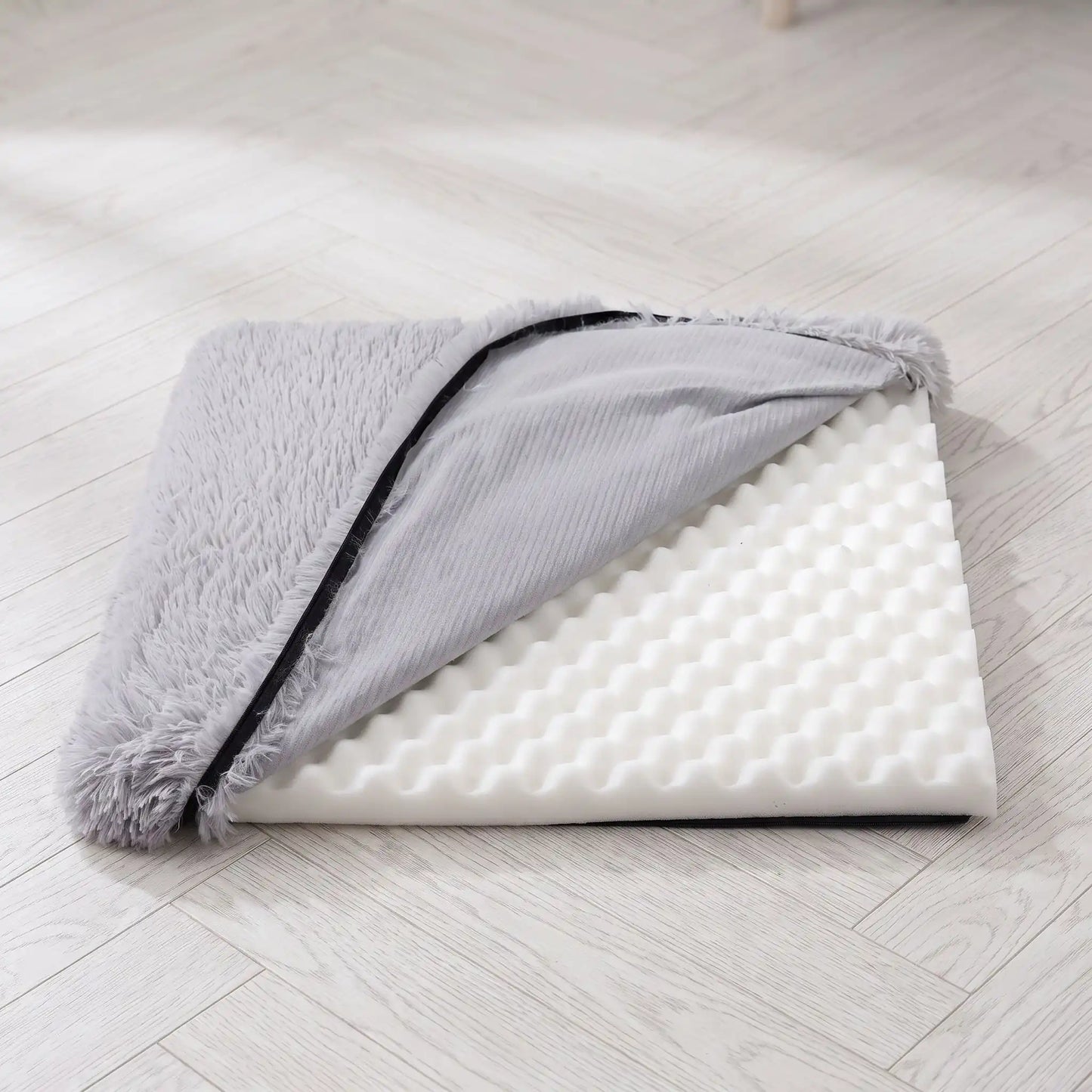 Coussin-déhoussable-pour-chien-chiot-lit-orthopédique-housse en peluche resistante et ultra douce, matelas à memoire de forme 100% coton haute résilience , housse 100% imperméable et antidérapant, lavavble en machien, rectangulaire, polyvalent : au sol, dans un panier, niche, cage interieur, cage de transport, etc. disponible en 4 tailles S, M L et XL pour chiot et chien de 0 à 35 kg max-gros plan sur le coussin en peluche gris clair déhoussé avec le matelas orthopédique visible et doublure imperméable 