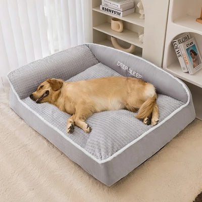 Coussin-pour-chien-xxl-matelas-à-mémoire-de-forme- avec-traversin en L rembourrage épais 100% coton haute densité ergonomique, imperméable antidérapant et déhoussable et lavable en machine pour chien de grande taille jusqu'à 50 kg max, résistant aux griffes et morsure- un  grand chien qui dort paisiblement et couché confortablement sur le flanc et de tout son long sur le lit rectangulaire de 120 cm de couleur gris dans la chambre de la maison