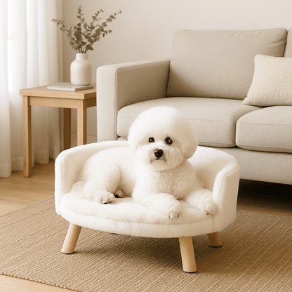 Fauteuil-pour-chien-imperméable-anti-stress-structure en bois naturel-coussin intérieur amovible, déhoussable et lavable en machine-surface douillette en peluche hypoallergénique rembourré 100% coton haute densité-sur pied en bois robuste et antidérapant-dossier arrondi et entourant-sécurisant et ergonomique-un petit chien blanc qui se détend paisiblement couché sur son mini canapé au design scandinave de couleur crème-surélevé dans la véranda de la maison
