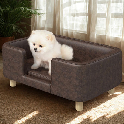 Fauteuil-pour-petit-chien-avec-pied-en bois massif-lit surélevé rectangulaire avec haut rebords anti-stress pour chiot et chien de petite taille-un Spitz nain assis confortablement sur le coussin du mini canapé pour chien design simil cuir marron imperméable et lavable dans le salon de l'appartement