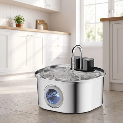 Fontaine-à-eau-chien-distributeur-automatique-inox 304D avec robinet verseur, avec batterie longue durée, rechargeable par USB, sans fil transportable, capacité de 3,2 litres, avec capteur de mouvement, 3 programmes : eau en continue, intermitence ou automatique avec filtre à 3 niveaux (charbon, coton, ions et éponge) design hublot sur le devant pour voir le niveau d'eau-gros plan sur la fontaine à eau automatique en mode intermittence pour chiot et chien de petite à moyenne taille sur le sol de la cuisine 