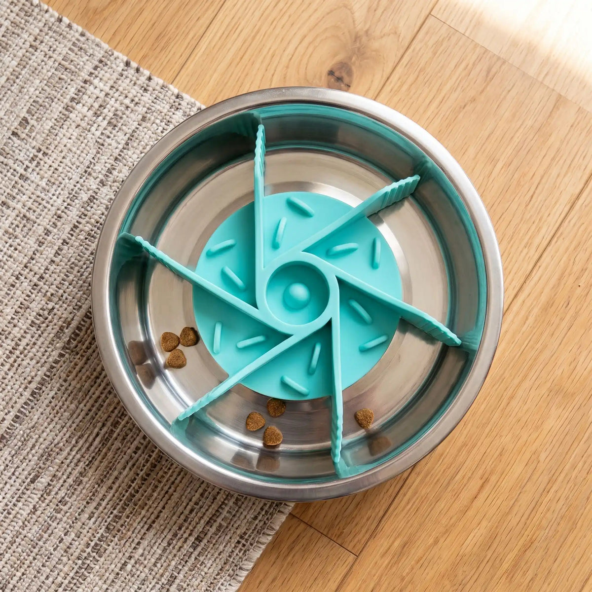 Gamelle-chien-anti-glouton-chiot-insert, adaptable à tous type de gamelle (grande, moyenne et petite) pour toute races de chiens, silicone alimentaire robuste, sans BPA, support avec 19 ventouses pour fixer l'insert dans le fond de la gamelle, labyrinthe pour ralentir l'ingestion trop rapide, diamètre réglable de 11 cm à 18 cm-gros plan sur l'insert anti glouton en forme de labyrinthe pour ralentir l'alimentation canine de couleur turquoise dans la gamelle en inox sur le sol de la cuisine