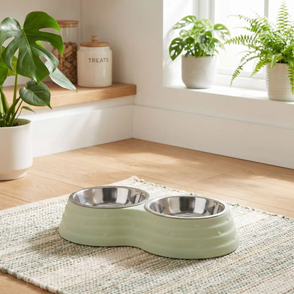 Gamelle-double-pour-chien et chiot amovible en inox , compatible au lave-vaisselle avec support en résine, design en 8 robuste, avec pieds antidérapants,anti-renversement disponible en 3 tailles pour chien de petite à moyenne race 200ml/500ml/700ml par bol et 3 coloris bleu, rose et vert-gros plan sur la double pour eau et nourriture pour chien dans son support surélevé en résine de couleur vert et ses pieds antidérapants, anti-glissement sur le tapis de sol dans le salon de l'appartement