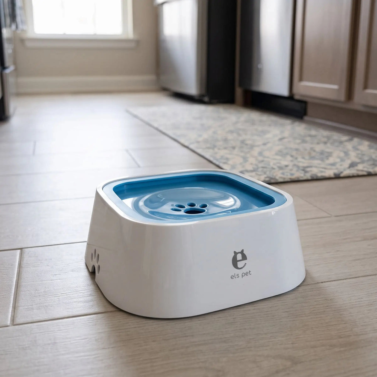 Gamelle-eau-chien-propre-1500ml pour chien et chiot anti-renversement, anti-bave, anti éclaboussures avec sa base évasée en bas et ses pieds antidérapants , sa base flottante et son contour qui bloque le tout,sans BPA, abs de qualité alimentaire,lavable en lave-vaisselle, démontable en 3 parties, robuste en 4 coloris : gris, blanc, bleu et rose- gros plan sur la  gamelle d'eau et fraiche de couleur bleu et blanc sur le sol en parquet propre de la cuisine de l'appartement