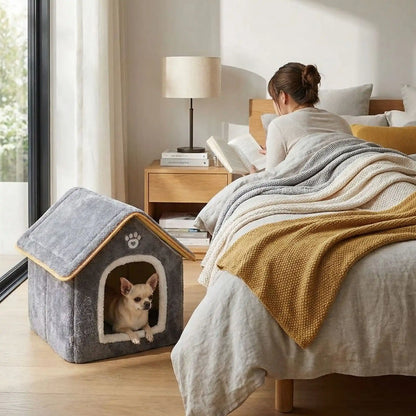 Maison-chien-intérieure-chiot-mini, pliable, légère et transportable, avec matériau isolant efficace contre le bruit et du froid, niche antidérapante, lavable en machine avec toit amovible, de couleur grise pour chiot et chien de 0 à 5 kg, disponible en taille XS et S- un chihuahua couché confortablement dans la petite niche intérieure sur le sol de la chambre à côté du lit de sa maitresse allongé qui lit son livre tranquillement
