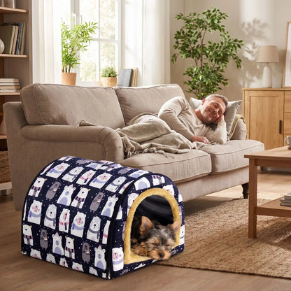 Niche-pour-chiot-petite-a-moyenne-race-pliable, résistante, en forme d'igloo au design sécurisant fermé en arc de cercle, intérieur en peluche douce et hypoallergénique avec un coussin rectangulaire au rembourrage 100% coton haute densité lavable, fond antidérapant et exterieur 100% imperméable, transportable avec sa poignée intégrée- un chiot de petite race qui dort  paisiblement dans sa niche à côté au pied du canapé où son maitre fait sa sieste dans le salon de l'appartement