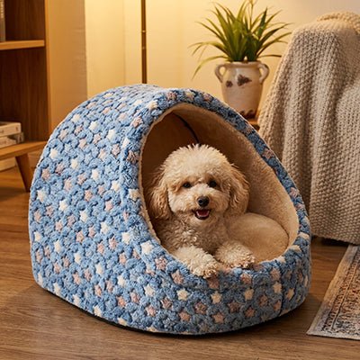 Panier-chien-niche-chiot-anti-anxiete-anti-stress avec coussin amovible déhoussable et lavable en machien, toucher velours, hypoallergénique et 100% coton haute densité avec motif étoiles en 3 coloris bleu, rose et marron pour les races de petits chiens, races naines et chiot-un caniche nain couché confortablement dans sa niche en demi cercle entourante, antidérapante qui protège des sols froids et des courants d'air dans le salon de la maison