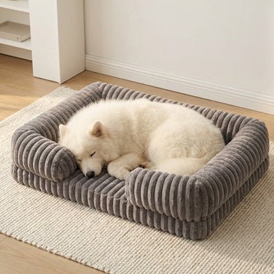 Panier-confort-chien-chiot-orthopédique-anti-stress confortable avec housse en velours doux et chaud imperméable et antidérapant résistant aux griffes et morsures vaec rebords surélevés au rembourrage 100% coton haute densité hypoallergénique en 3 tailles M, L et XL pour chien et chiot de 0 à 40 kilos-un chien de taille moyenne qui dort niché en boule contre les  rebords rembourrés et cylindriques du panier douillet et sécurisant avec matelas à mémoire de forme et velours doux de couleur gris foncé 