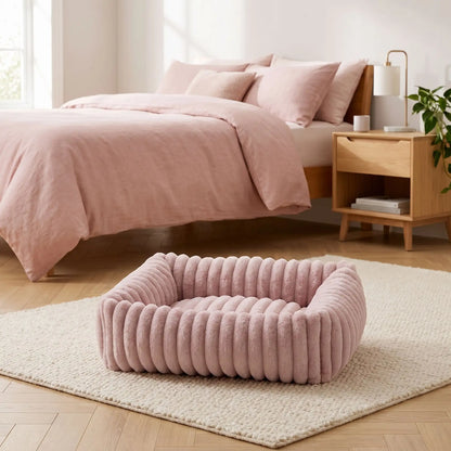 Panier-petit-chien-chiot-velours-confortable rectangulaire en velours ultra doux et résistant avec rebord 360° surélevé pour un effet cocon apaisant et rassurant anti-stress pour chien de petite taille de 0 à 9 kilos max, lavable en machine,épais rembourrage 100% Coton haute densité, fond imperméable et antidérapant-gros plan sur le panier pour petit chien et chiot rectangulaire  douillet et rembourrage généreux 100% coton haute résilience de couleur rose sur le sol de la chambre de l'appartement