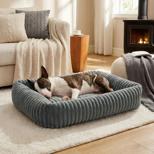 Panier-pour-chien-chiot-confort-velours, ergonomique avec son rembourrage 100% coton haute densité à mémoire de forme, lit chaud et apaisant, anti stress et anxiété avec son rebord surélevé sur 360° de forme rectangulaire, antidérapant et fond imperméable, lavable en machine-un Bull Terrier qui dort pasiblement couché sur le flanc, sa tête calée dans le rebord surélevé qui entoure tout son corps pour une relaxation complète dans le salon de la maison