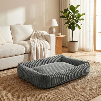 Panier-pour-chien-chiot-confort-velours, ergonomique avec son rembourrage 100% coton haute densité à mémoire de forme, lit chaud et apaisant, anti stress et anxiété avec son rebord surélevé sur 360° de forme rectangulaire, antidérapant et fond imperméable, lavable en machine-gros plan sur le panier de couleur gris en taille L pour chien de taille moyenne jusqu'à 15 kilos maximum sur le sol du salon de l'appartement