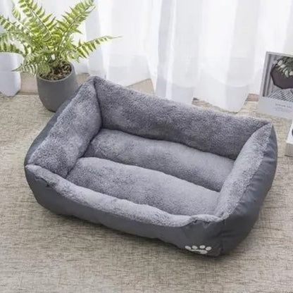 Panier-pour-chiot-douillet, intérieur en peluche ultra douce et hypoallergénique, housse en tissu résistant oxford 100% imperméable, coussin rectangulaire au rembourrage épais 100% coton haute densité, avec rebords surélevés épais et sécurisant, antidérapant et imperméable, lavable en machine, en 4 tailles de XS au L pour chiot de 0 à 20 kilos-gros plan sur le panier moelleux et ergonomique de couleur gris avec rebords surélevé et entrée abaissée et joli design d'empreinte de pattes de chien sur le côté