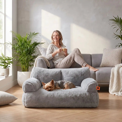 Petit-canapé-pour-chien-chiot-déhoussable en peluche lavable en machine, antidérapante et imperméable de couleur gris, rembourrage 100% coton haute densité ergonomique avec dossier et accoudoirs enveloppant pour chiot et chien de petite race de 0 à 7 kilos max-un petit chien couché confortablement dans son petit canapé gris foncé épais et rembourré 100% coton haute résilience ergonomique au pied de sa maitresse assisse sur son canapé dans le salon de l'appartement