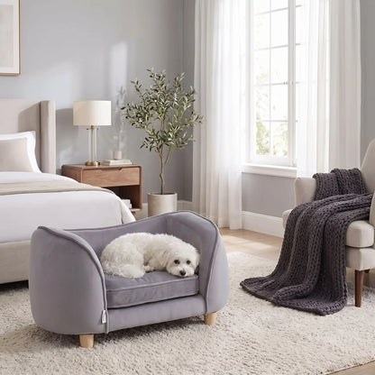 Petit-fauteuil-pour-chien-chiot-coussin intérieur épais au rembourrage 100% coton ergonomique, velours doux et résistant aux griffes, imperméable déhoussable et lavable en machine, de couleur gris, au design enveloppant en forme bateau structrure en bois massif avec 4 pieds à vissés en bois massif et robuste pour chiot et chien de petite taille à moyenne taille-un chien de petite taille qui dort paisiblement enveloppé dans son fauteuil avec son haut dossier au pieds du lit de ses maitres dans la chambre