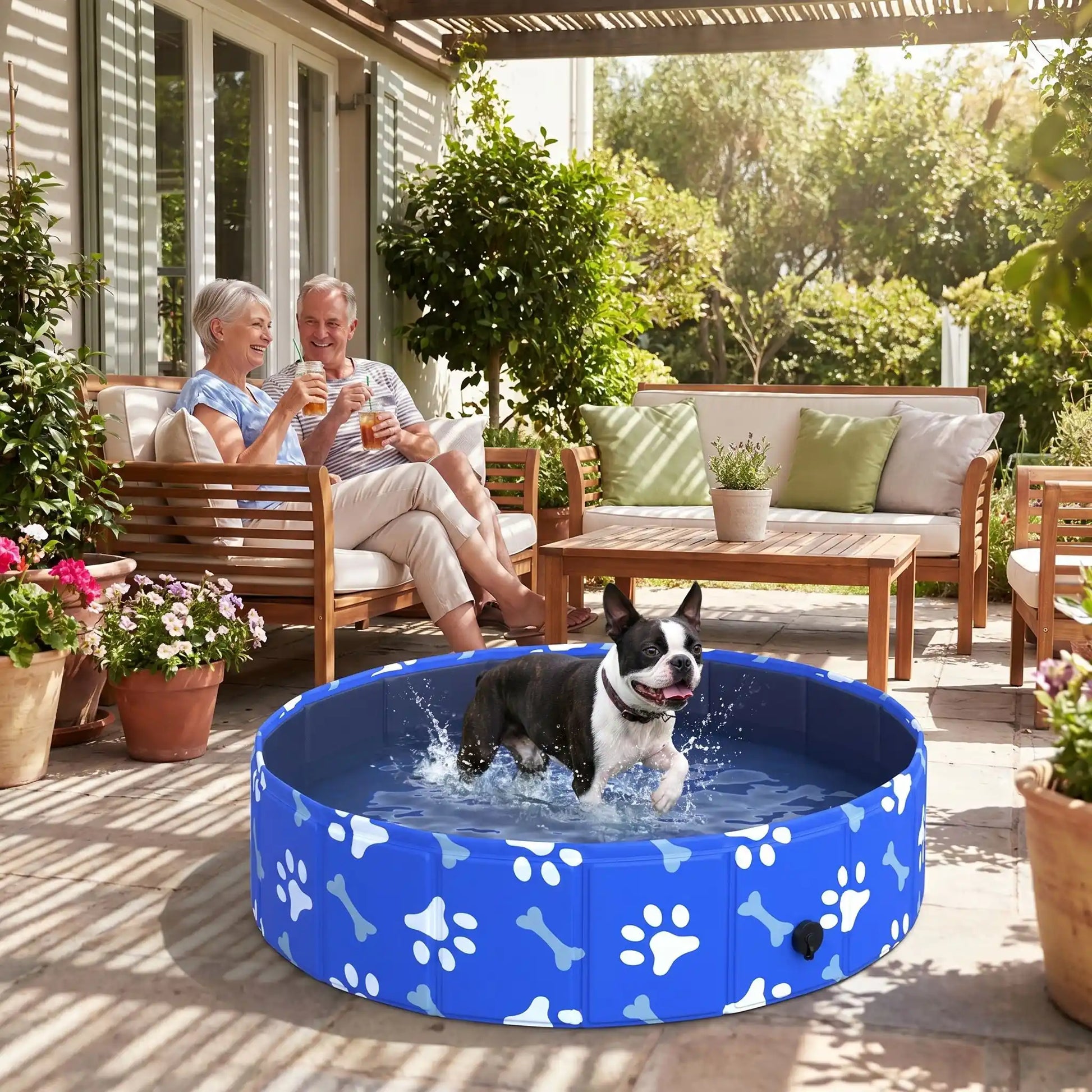 Piscine-rigide-pour-chien-rigide en panneaux MDF robuste anti-affaissement, pliable et lavable de diamètre 80 cm et de 20 cm de hauteur étudié pour une entrée et sortie facile et sécurisé pour le chien avec bouchon de vidange pratique et rapide, polyvalente piscine à balle, bassin, baignoire pour toilettage-un chien de taille moyenne qui se baigne avec bonheur sous le regard souriant de ses maitres qui déjeunent sur la terrasse ombragée de la maison en été