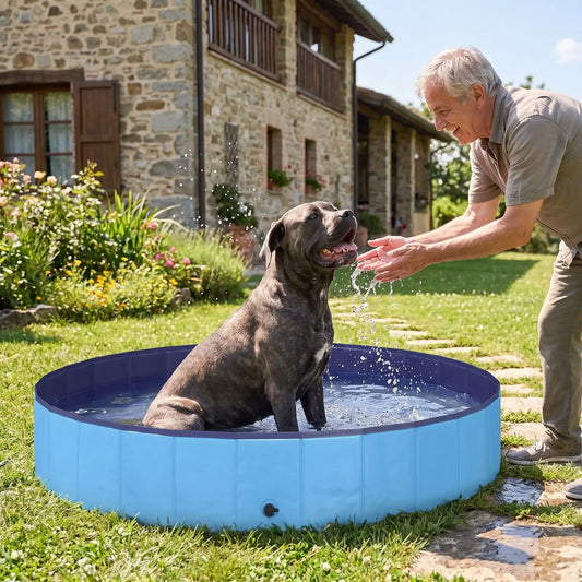 Piscine-pour-grand-chien-rigide-xxl, panneaux MDF robuste anti-affaissement, pliable et lavable de diamètre 200 cm et de 30 cm de hauteur étudiée pour une entrée et sortie facile et sécurisé pour le chien avec bouchon de vidange pratique et rapide, polyvalente piscine à balle, bassin, baignoire pour toilettage-un chien de grande race qui se rafraichit pour supporter la chaleur dans sa grande piscine robuste avec son maitre qui le mouille délicatement dans le jardin de la maison en été