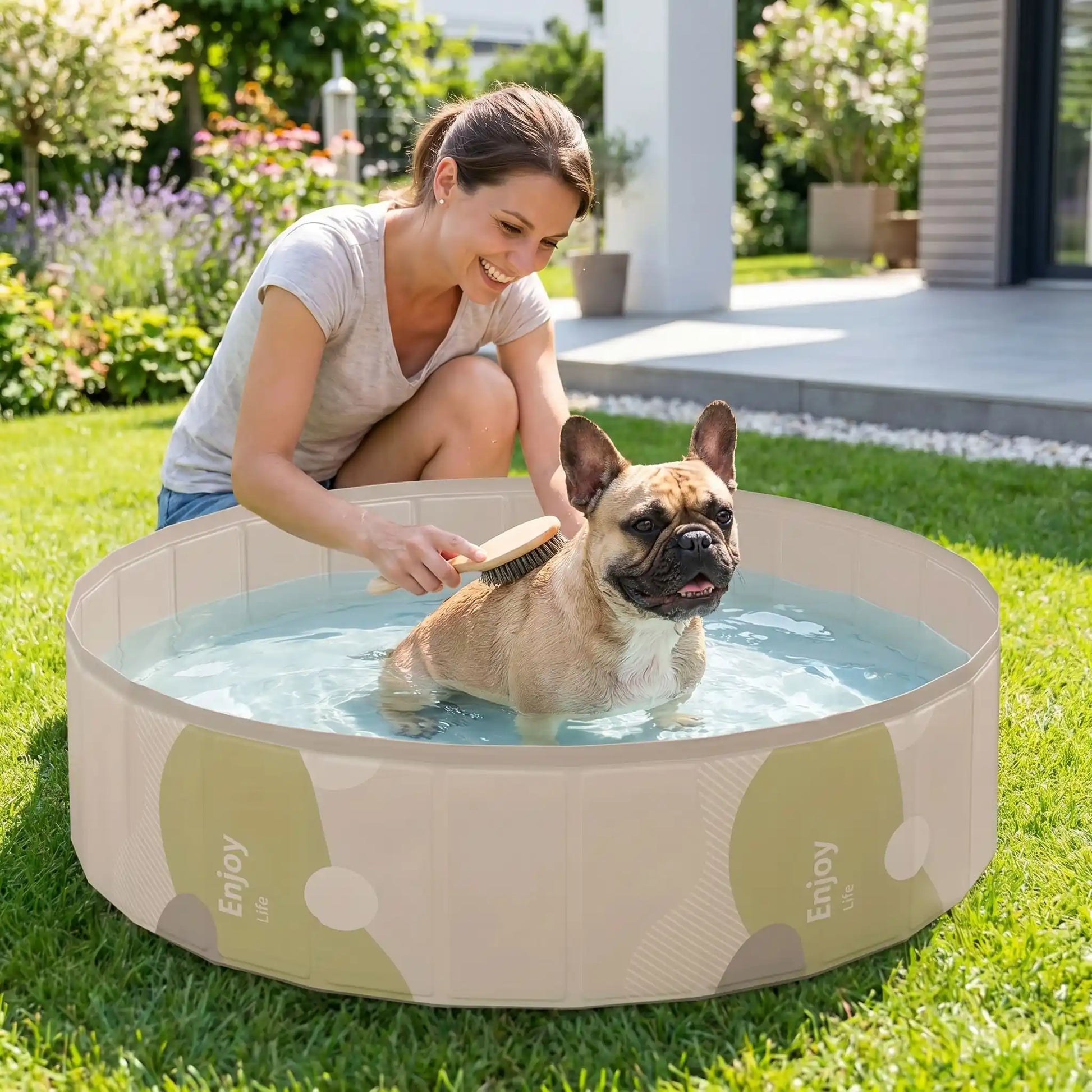 Piscines-pour-chiens-rigide en panneaux MDF robuste anti-affaissement, PVC sans produits toxiques , pliable et lavable de diamètre 80/100/120 cm et de 20/30 cm de hauteur étudié pour une entrée et sortie facile et sécurisé pour le chien avec bouchon de vidange pratique et rapide, polyvalente piscine à balle, bassin, baignoire pour toilettage-un petit chien qui se fait toiletter dans la piscine remplie d'eau  par sa maitresse souriante pour un moment complice maitre-chien dans le jardin du pavillon en été