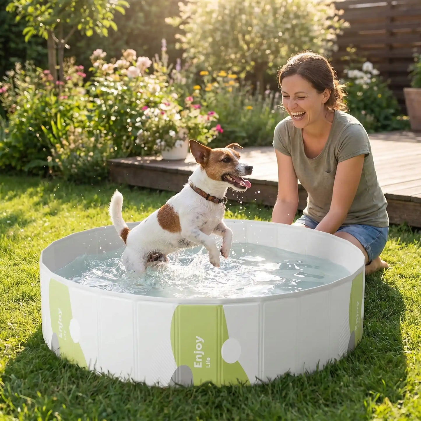 Piscines-pour-chiens-rigide en panneaux MDF robuste anti-affaissement, PVC sans produits toxiques , pliable et lavable de diamètre 80/100/120 cm et de 20/30 cm de hauteur étudié pour une entrée et sortie facile et sécurisé pour le chien avec bouchon de vidange pratique et rapide, polyvalente piscine à balle, bassin, baignoire pour toilettage-un petit chien qui saute heureux de se rafraichir en été dans la piscine remplie d'eau avec sa maitresse assise sur la pelouse à côté de lui et qui le regarde en riant