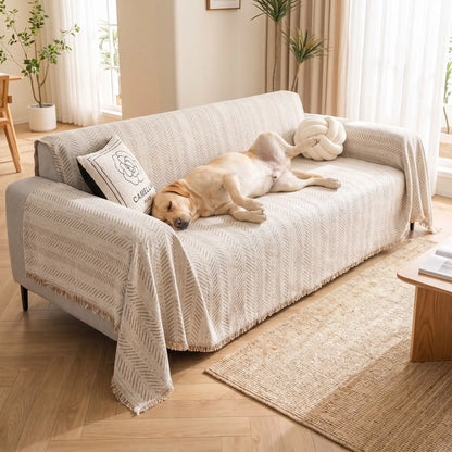 Protection-canapé-chien-bohême-anti-poils-résistante aux griffes, tissage chenille coton et polyester, écoresponsable avec franges pour un style bohème chic de couleur blanc cassé, dispoinble en 4 tailles pour fauteuil/canapé une place, deux places, 3 places et 4 places, lavable en machine, doux respirant confortable et 4 saisons-un chien de grande race couché les pattes en l'air sur le plaid qui protège le grand canapé avec accoudoirs dans le salon de la maison