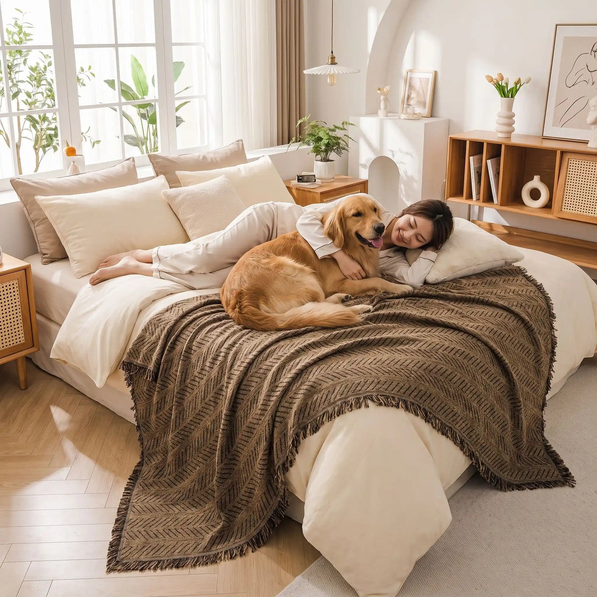 Protection-canape-chien--anti-poils-résistante aux griffes, tissage chenille coton et polyester, écoresponsable avec franges pour un style bohème chic de couleur marron, disponible en 4 tailles pour fauteuil/canapé une place, deux places, 3 places et 4 places, lavable en machine, doux respirant confortable et 4 saisons-un grand chien et sa maitresse allongés pour un câlin sur le plaid marron qui protège le lit de la chambre de la maison