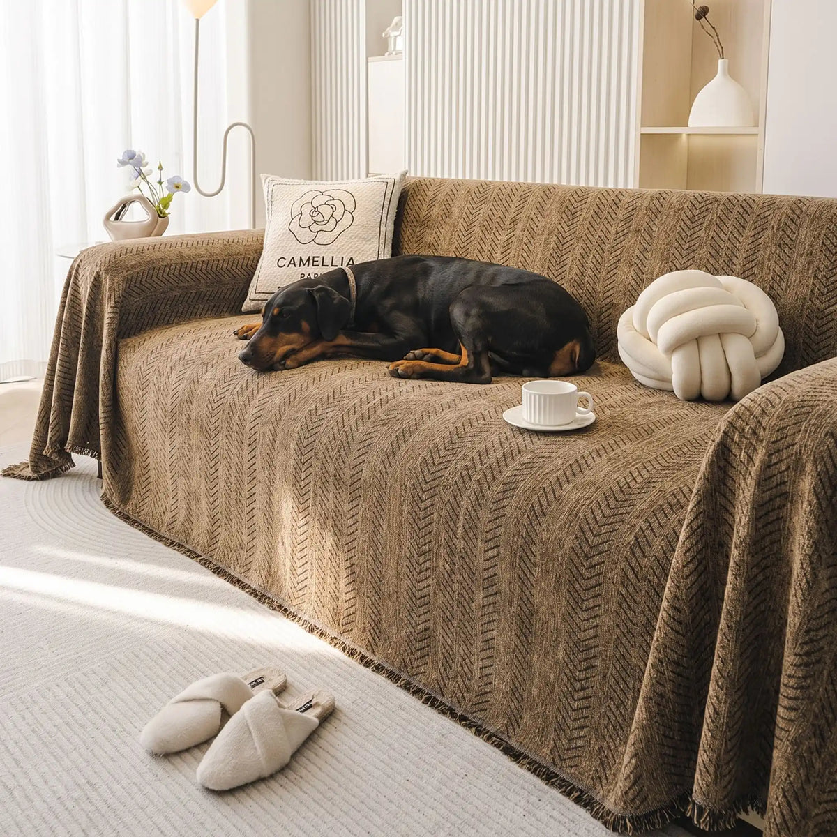 Protection-canape-chien--anti-poils-résistante aux griffes, tissage chenille coton et polyester, écoresponsable avec franges pour un style bohème chic de couleur marron, disponible en 4 tailles pour fauteuil/canapé une place, deux places, 3 places et 4 places, lavable en machine, doux respirant confortable et 4 saisons- un chien de grande race confortablement couché sur le plaid de protection qui couvre entièrement le grand canapé avec un style bohême chic avec son tissage solide artisanal