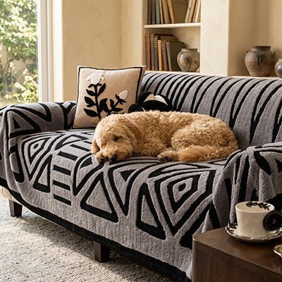 Protection-canape-chien-chiot-plaid chaud et épais, antidérapant et coutures solides, lavable en machine à laver avec design déométrique moderne pour couvrir et protéger le canapé, lit ou mobilier des poils et tâches des chiens, écoresponsable et résistantes aux griffes-un chien de taille moyenne qui dort en boule paisiblement sur la protection de couleur gris clair et motif noir sur le canapé 4 places dans le salon de l'appartement
