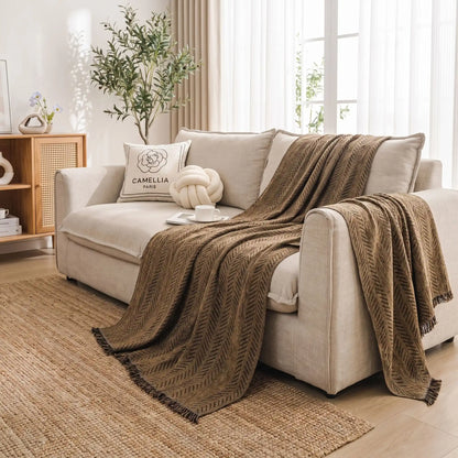 Protection-canape-chien--anti-poils-résistante aux griffes, tissage chenille coton et polyester, écoresponsable avec franges pour un style bohème chic de couleur marron, disponible en 4 tailles pour fauteuil/canapé une place, deux places, 3 places et 4 places, lavable en machine, doux respirant confortable et 4 saisons-gros plan sur le plaid au tissage artisanale avec 350mg de coton doux et confortable posé sur le canapé du salon pour montrer sa souplesse