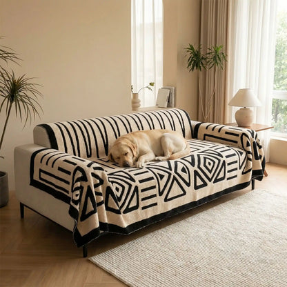 Protection-canape-chien-chiot-plaid chaud et épais, antidérapant et coutures solides, lavable en machine à laver avec design déométrique moderne pour couvrir et protéger le canapé, lit ou mobilier des poils et tâches des chiens, écoresponsable et résistantes aux griffes-un grand chien qui dort couché sur la protection canapé blanc aux motifs géométriques noir sur le canapé du salon de l'appartement