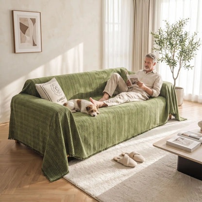 Protège-canapé-chien-anti-poils-résistante aux griffes, tissage chenille coton et polyester tissé résistant, écoresponsable avec franges pour un style bohème chic de couleur vert olive, disponible en 4 tailles pour fauteuil/canapé une place, deux places, 3 places et 4 places, lavable en machine, doux respirant confortable et 4 saisons-un maitre et son chien tout les deux allongés confortablement sur le protège canapé vert olive dans le salon de l'appartement