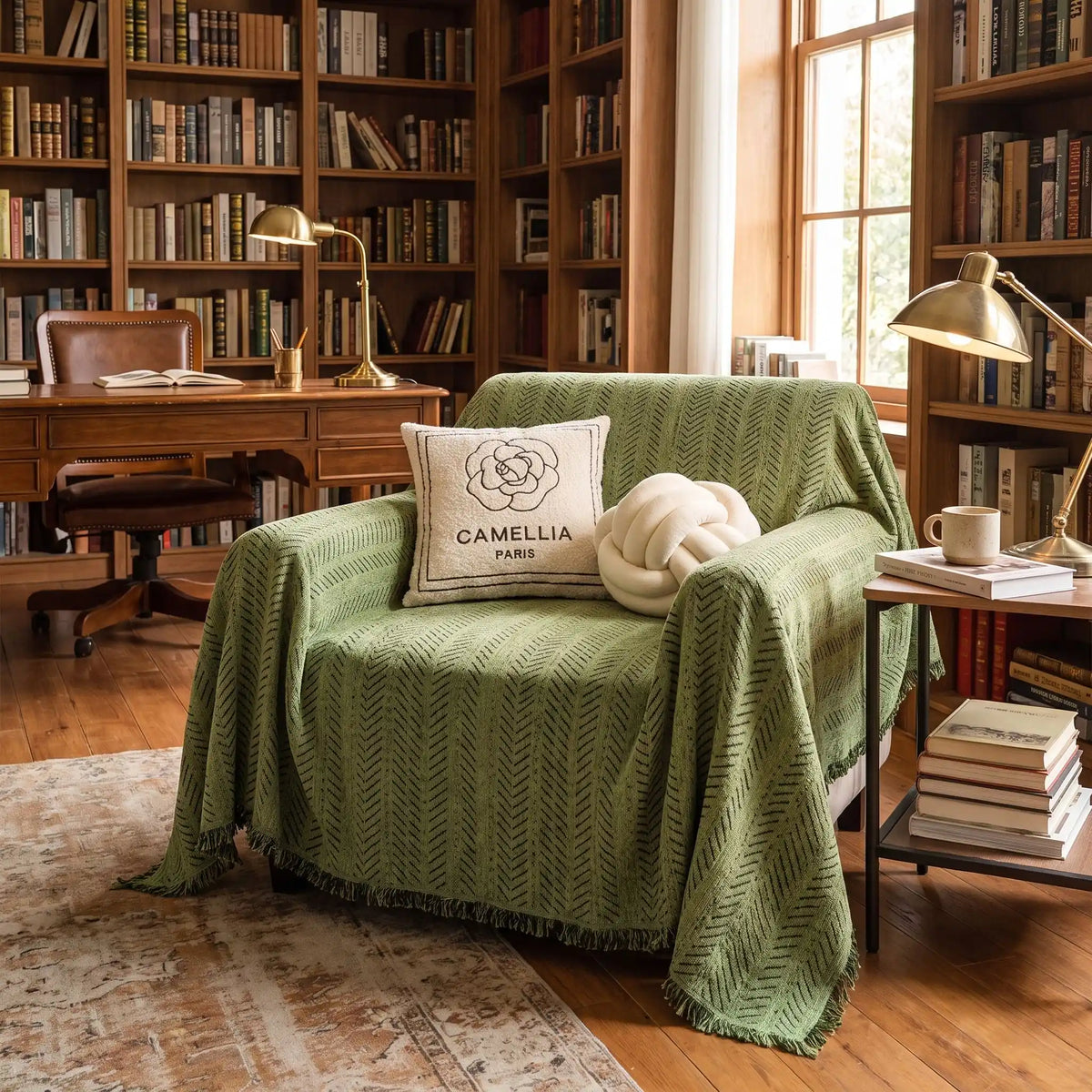 Protège-canapé-chien-anti-poils-résistante aux griffes, tissage chenille coton et polyester tissé résistant, écoresponsable avec franges pour un style bohème chic de couleur vert olive, disponible en 4 tailles pour fauteuil/canapé une place, deux places, 3 places et 4 places, lavable en machine, doux respirant confortable et 4 saisons- gros plan sur le plaid de protection installé sur le fauteuil une place dans la bibliothèque de la maison