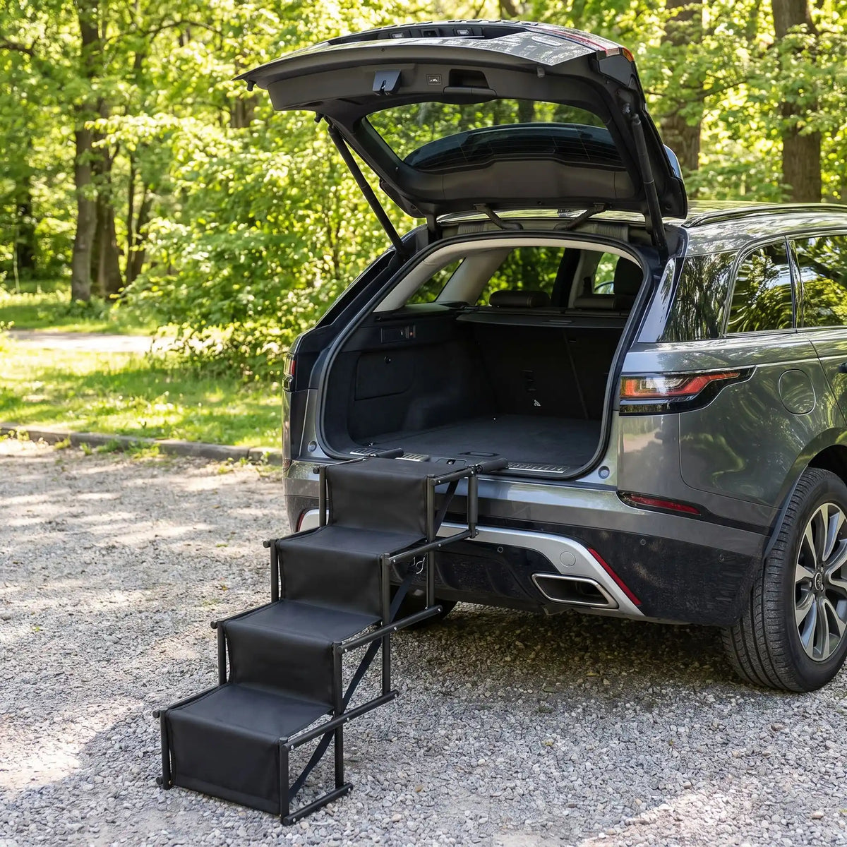 Rampe-escalier-pour-chien-chiot-pliable-voiture en acier oxydable et tissu oxford résistant aux griffes, antidérapant et 100% imperméable, pliage en accordéon, ouverture rapide et facile en un geste, poignées en mousse anti-rayures, légère avec sangles de transport de 4 marches avec hauteurs modulables 56 à 76 cm pour chien de moyenne à grande taille de 30 à 75 kilos max-gros plan sur la rampe escalier de 4 marches dépliables de couleur noir contre le coffre du SUV pour un accès facile pour les chien
