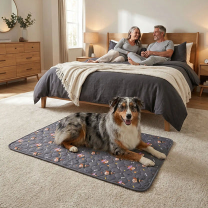 Tapis-impermeable-chien-chiot-motif design de bouledogue francais, os et pattes de chien, surface matelassée douce et hypoallergénique, rembourré en coton haute densité ultra-absorbant, 4 couches avec TPU 100% imperméable et résistant aux griffes, antidérapant, lavable en machine à 30° de couleur gris en 4 taille M, L, XL et XXL pour chiot et chien de petite à très grande taille-un chien de race moyenne couché confortablement sur son tapis gris sur le sol de la moquette au pied du lit de ses maitres 