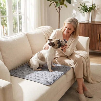 Tapis hygiène chien, chiot, propreté, absorbant-chien-chiot-motif design de coeur, os et pattes de chien, surface matelassée douce et hypoallergénique, rembourré en coton haute densité ultra-absorbant, 4 couches avec TPU 100% imperméable et résistant aux griffes, antidérapant, lavable en machine  de couleur gris en 4 taille M, L, XL et XXL pour chiot et chien de petite à très grande taille-un chien moyen couché confortablement sur son tapis gris sur le canapé en protection à côté de sa maitresse 