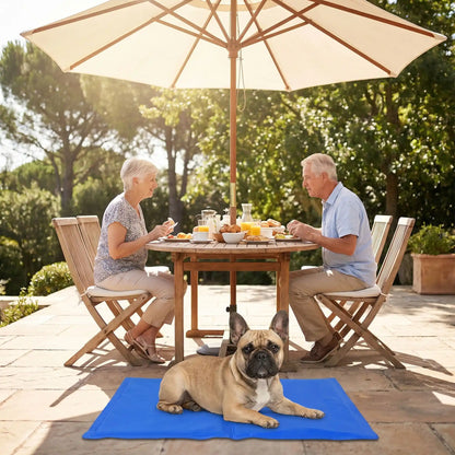 Tapis-pour-chien-rafraichissant-gel-garanti sans produits toxiques et sans danger, de couleur bleu, avec eponge ergonomique intérieur, gel composé de 98% d'eau, tissu extérieur résistant aux griffes et confortable pour la peau en nylon, pliable et transportable-utilisable comme couchage au sol, panier, voiture, niche, lit pour chiot et chien-4-tailles disponible en XS, S, M et L- un Bouledogue français couché confortablement sur son tapis frais sur la terasse , au pied de ses maitres qui dejeunent 